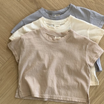 Drei pastellfarbene Basic-T-Shirts von Bebe Holic in Beige-, Creme- und Hellgrautönen sind ordentlich auf einem hölzernen Boden mit Fischgrätenmuster gestapelt. Diese T-Shirts aus hochwertiger Baumwolle haben eine lässige, entspannte Passform und kurze Ärmel in natürlichen Tönen.